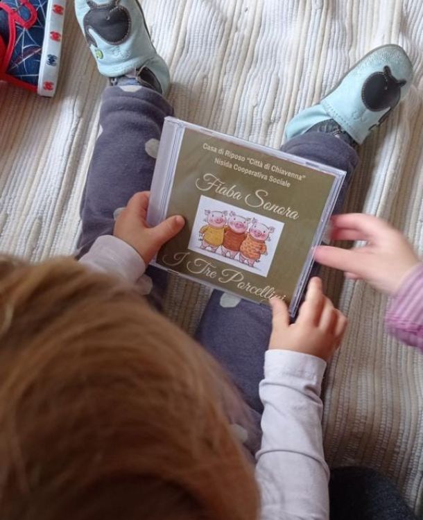 bambino che tiene in mano cd della fiaba sonora dei 3 porcellini